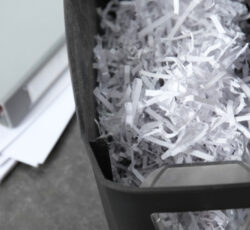 Document,shredder,with,paper,shreds,on,table,,closeup